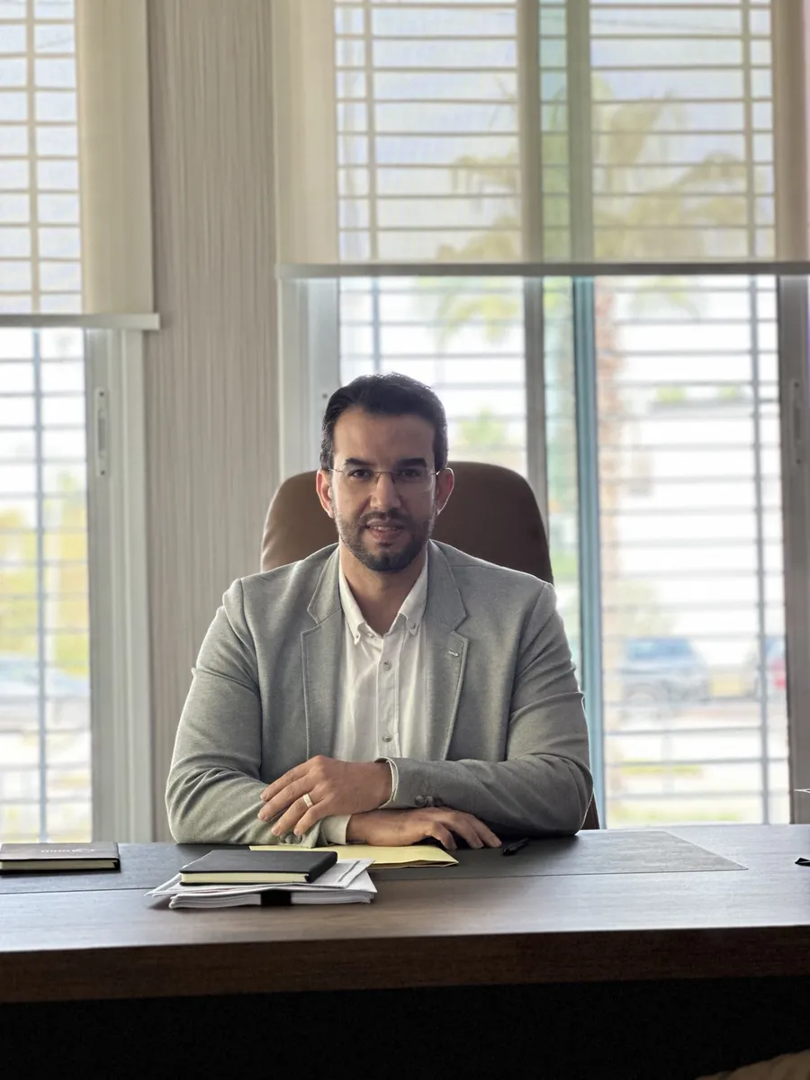 Abdelmajid Charrass assise face a l’objectif derrière un bureau, veste grise.