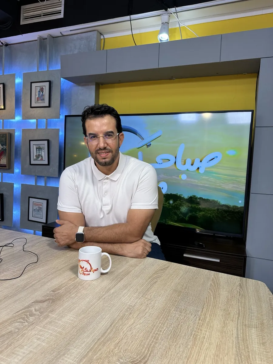 Abdelmajid Charrass assise dans un plateau télévision en polo blanc.