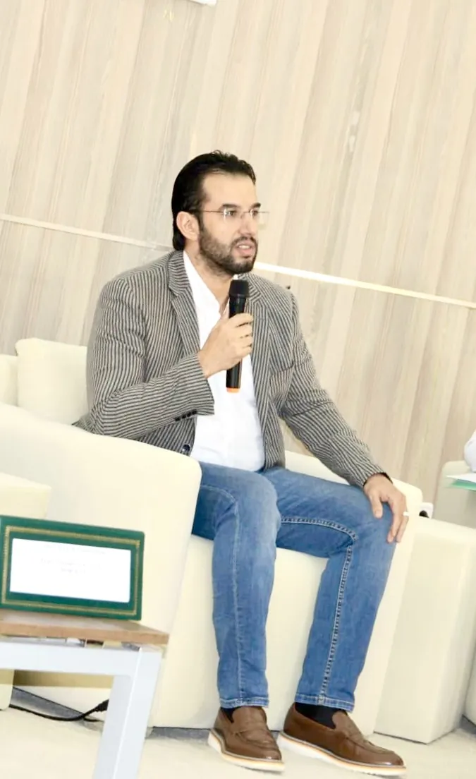 Abdelmajid Charrass en costume gris assis dans un fauteuil lors d’un panel.